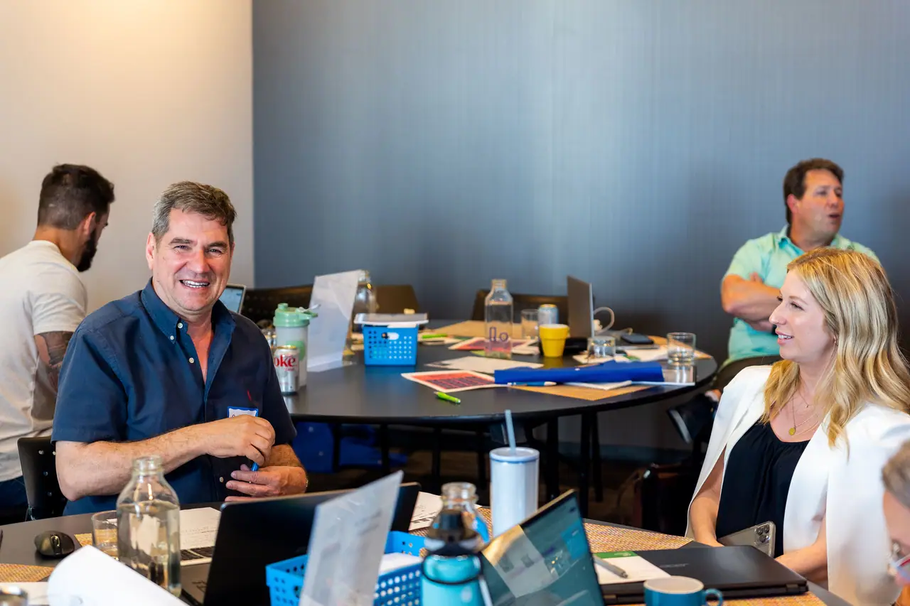 Des entrepreneurs souriants autour de tables de travail pendant un atelier de groupe